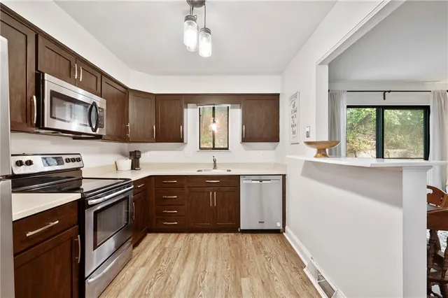 a kitchen with stainless steel appliances granite countertop wooden cabinets a stove top oven a sink and dishwasher