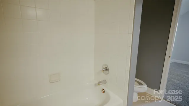 a view of a hallway with wooden floor and a bathroom