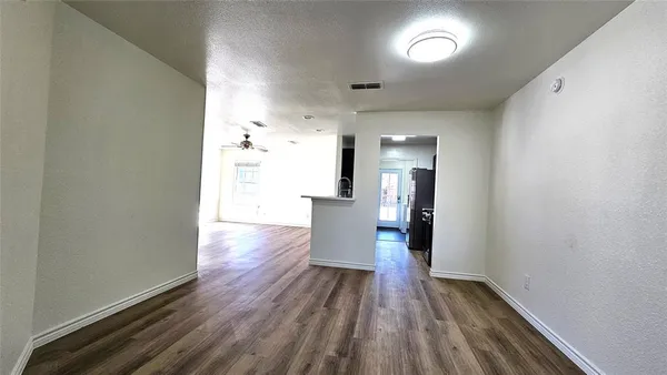 a view of an empty room with window and wooden floor