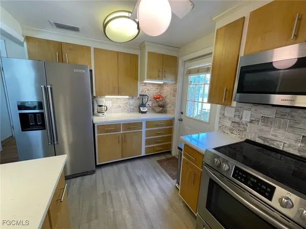 a kitchen with stainless steel appliances a stove a refrigerator a sink a dining table and chairs