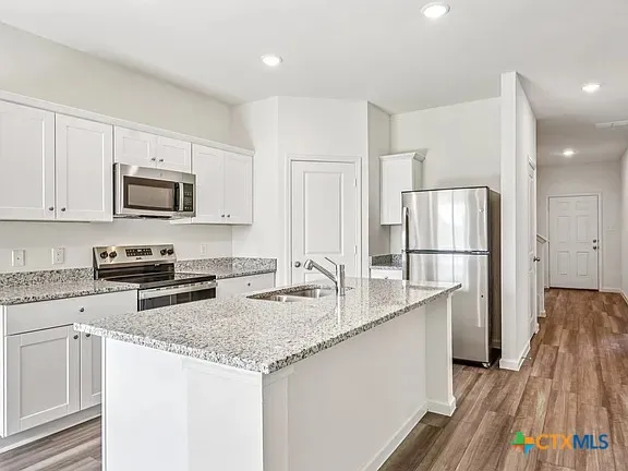 a kitchen with granite countertop a sink stove and refrigerator