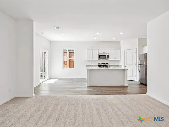 a view of kitchen with granite countertop cabinets and refrigerator