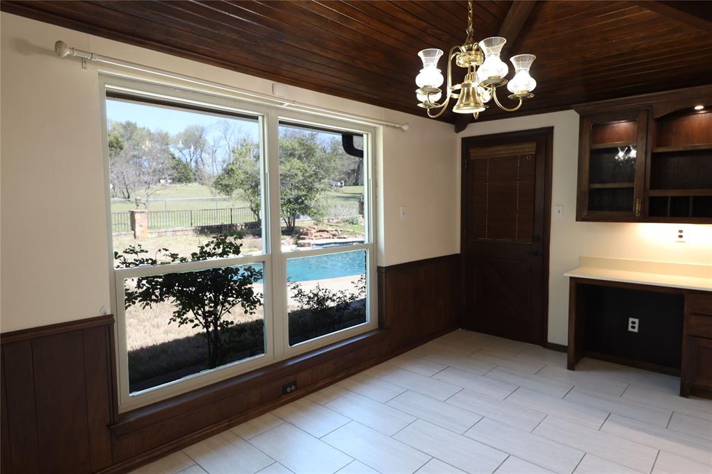 907 Red Oak Creek Road Ovilla, TX 75154 - Photo 7 of 20 Bright interior space featuring a large window overlooking an outdoor swimming pool, a wood-paneled ceiling, and light-colored tile flooring