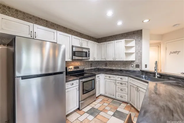 a kitchen with stainless steel appliances granite countertop a refrigerator a stove a sink and a microwave