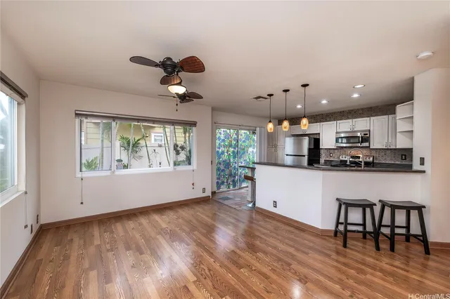 a kitchen with stainless steel appliances granite countertop a stove top oven a sink dishwasher a dining table and chairs with wooden floor