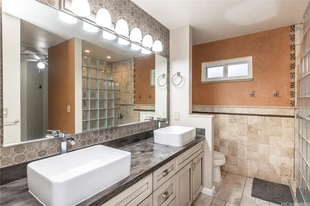 a bathroom with a granite countertop double vanity sink a mirror and a shower