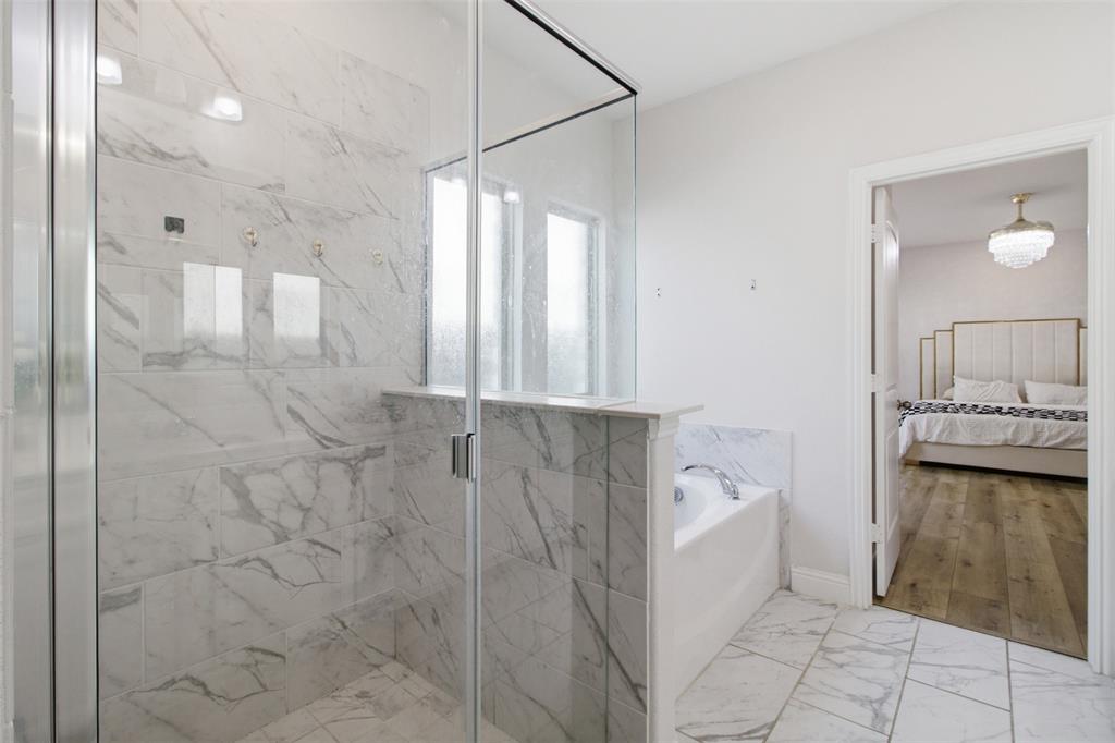 7416 Sequoia Rdg Road Little Elm, TX 76227 - Photo 29 of 37 Spacious bathroom featuring a glass-enclosed shower with large format marble-look tile, a built-in bathtub with matching marble-look surround, and tiled flooring