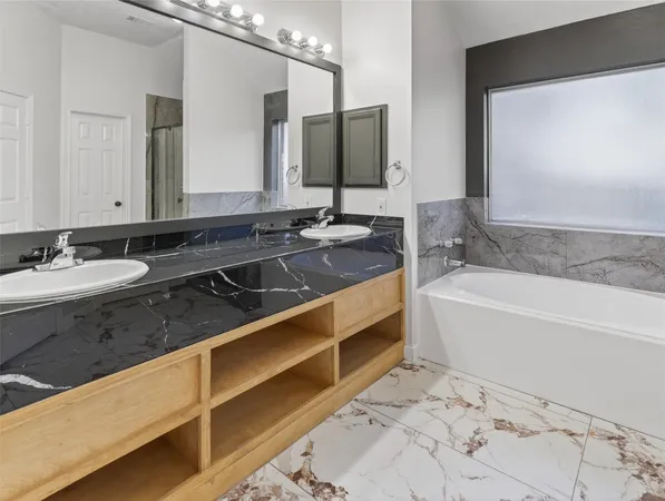 a bathroom with a bathtub and a double vanity sink