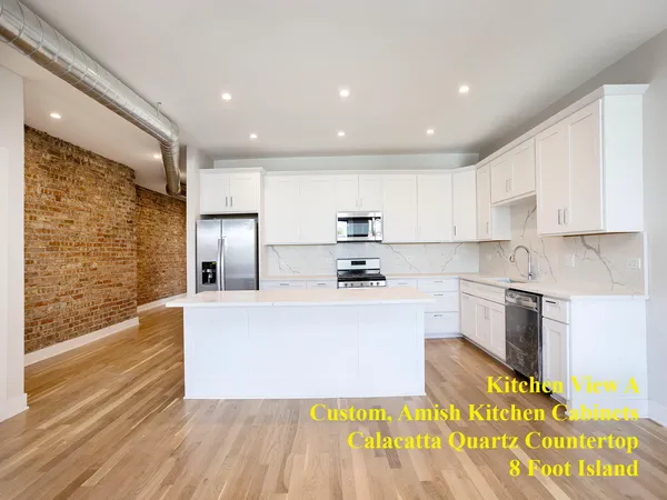 a large kitchen with stainless steel appliances a large counter top a stove and a refrigerator