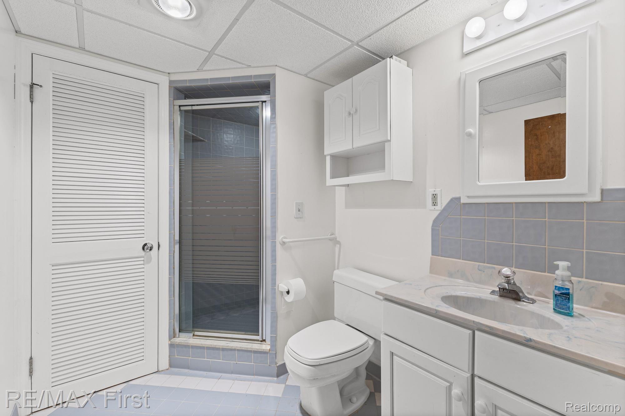 34356 Greentrees Road Sterling Heights, MI 48312 - Photo 33 of 40 Bathroom with vanity, a stall shower, a drop ceiling, backsplash, and light tile patterned floors