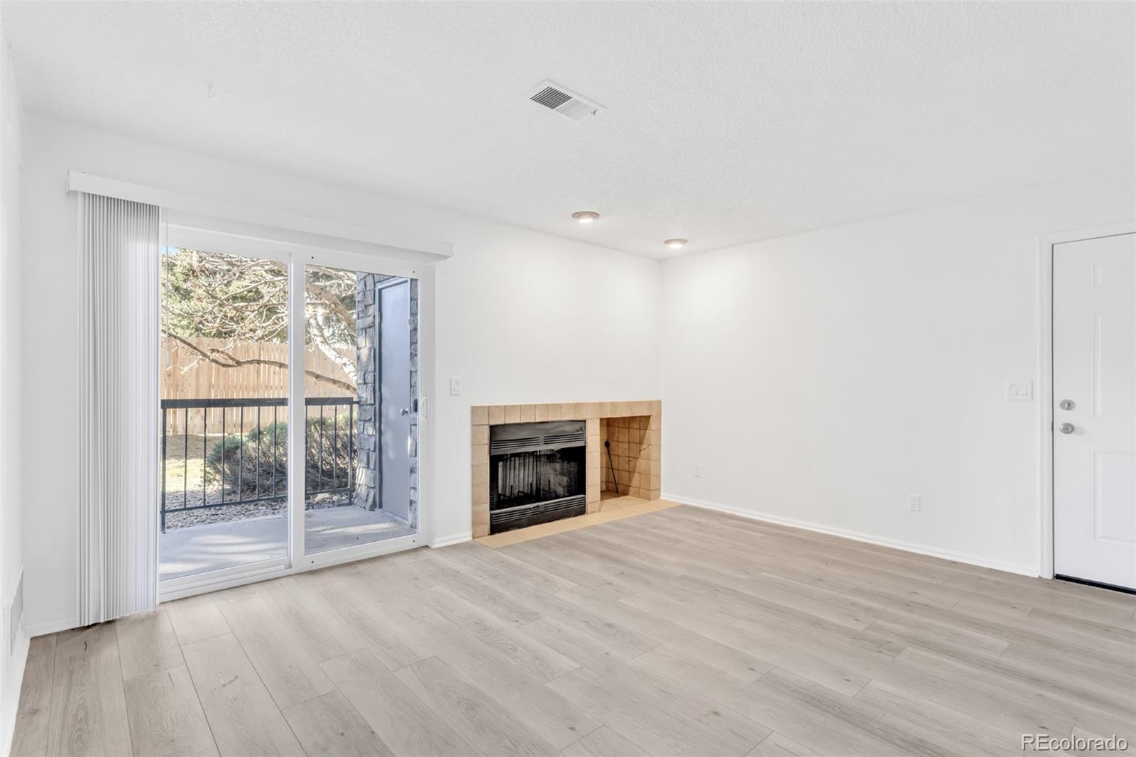 2575 South Syracuse Way, Unit J108 Denver, CO 80231 - Photo 3 of 18 a view of an empty room with a fireplace and a window