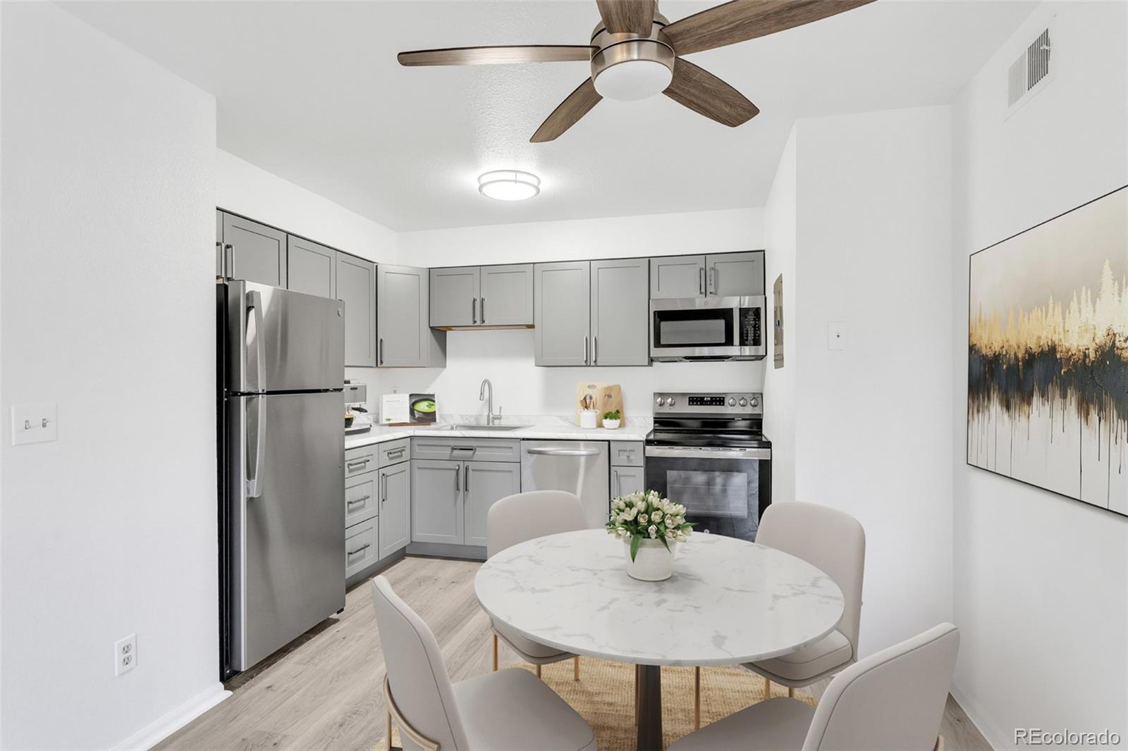 2575 South Syracuse Way, Unit J108 Denver, CO 80231 - Photo 4 of 18 a kitchen with stainless steel appliances granite countertop a refrigerator a stove a microwave oven a sink with island and chairs