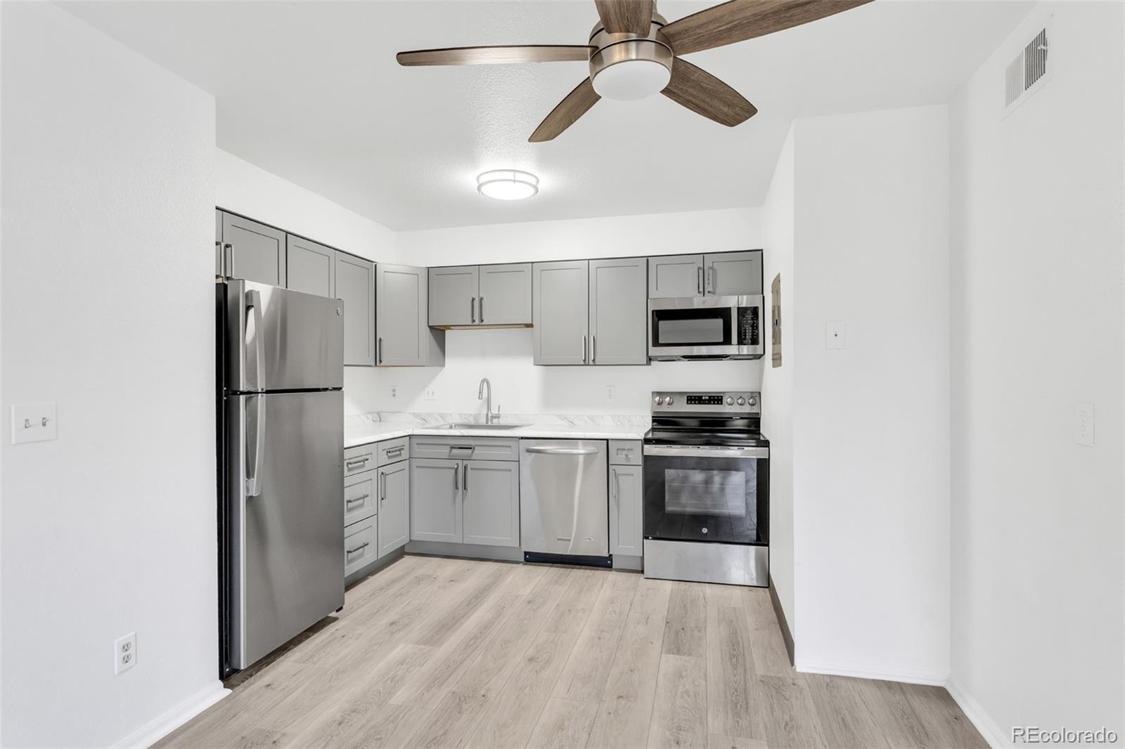 2575 South Syracuse Way, Unit J108 Denver, CO 80231 - Photo 5 of 18 a kitchen with stainless steel appliances granite countertop a refrigerator and a stove top oven