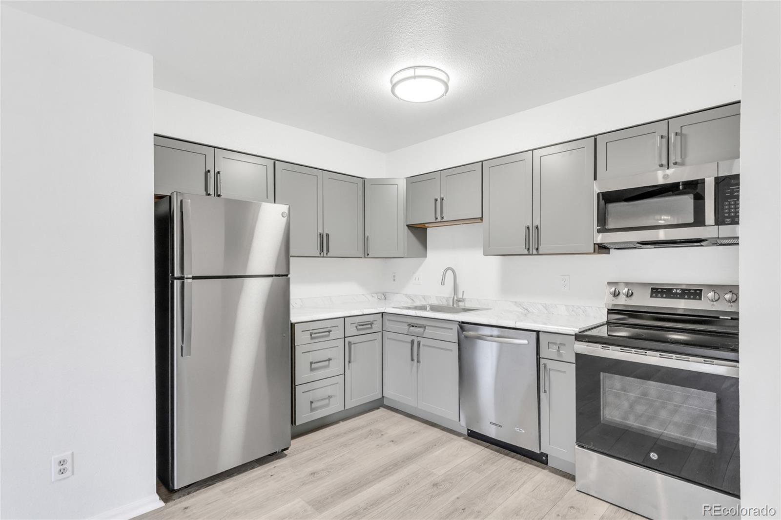 2575 South Syracuse Way, Unit J108 Denver, CO 80231 - Photo 6 of 18 a kitchen with appliances a sink and lots of appliances