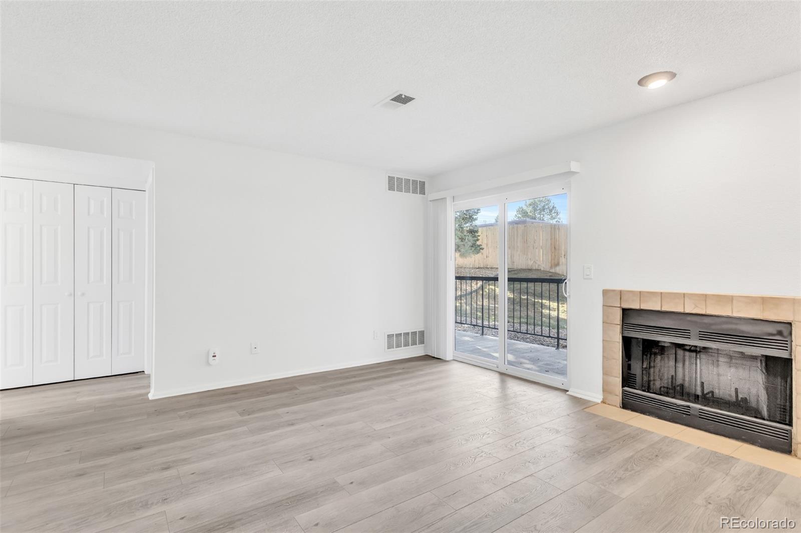 2575 South Syracuse Way, Unit J108 Denver, CO 80231 - Photo 7 of 18 an empty room with wooden floor fireplace and windows