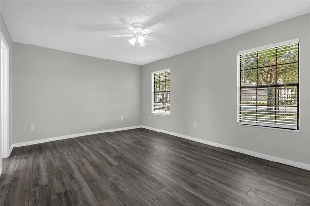 a view of an empty room with a window and wooden floor