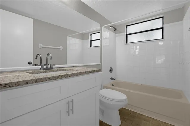 a bathroom with a granite countertop sink a toilet and shower