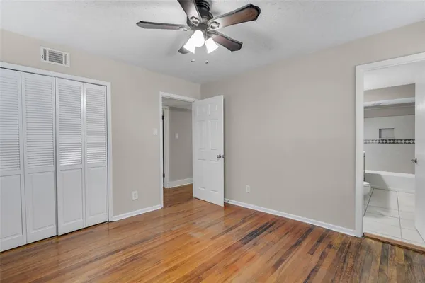 an empty room with wooden floor and a ceiling fan