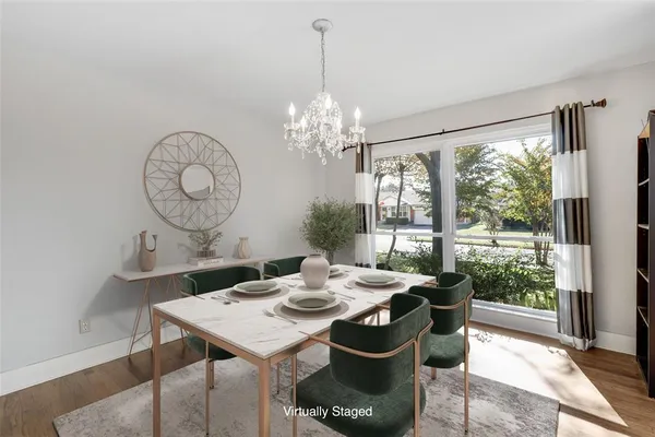 a view of a dining room with furniture a chandelier and large windows