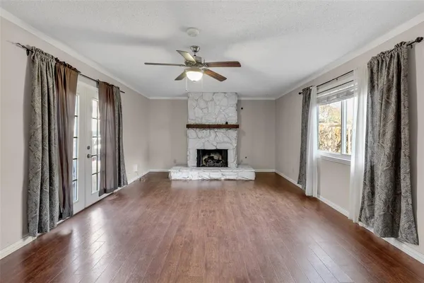 a view of an empty room with wooden floor fireplace and a window