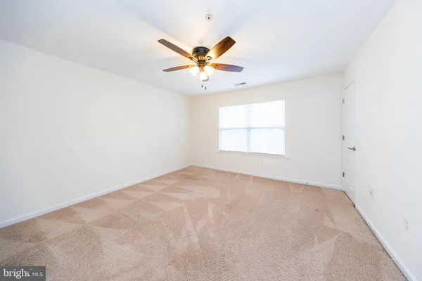 an empty room with a window and a ceiling fan