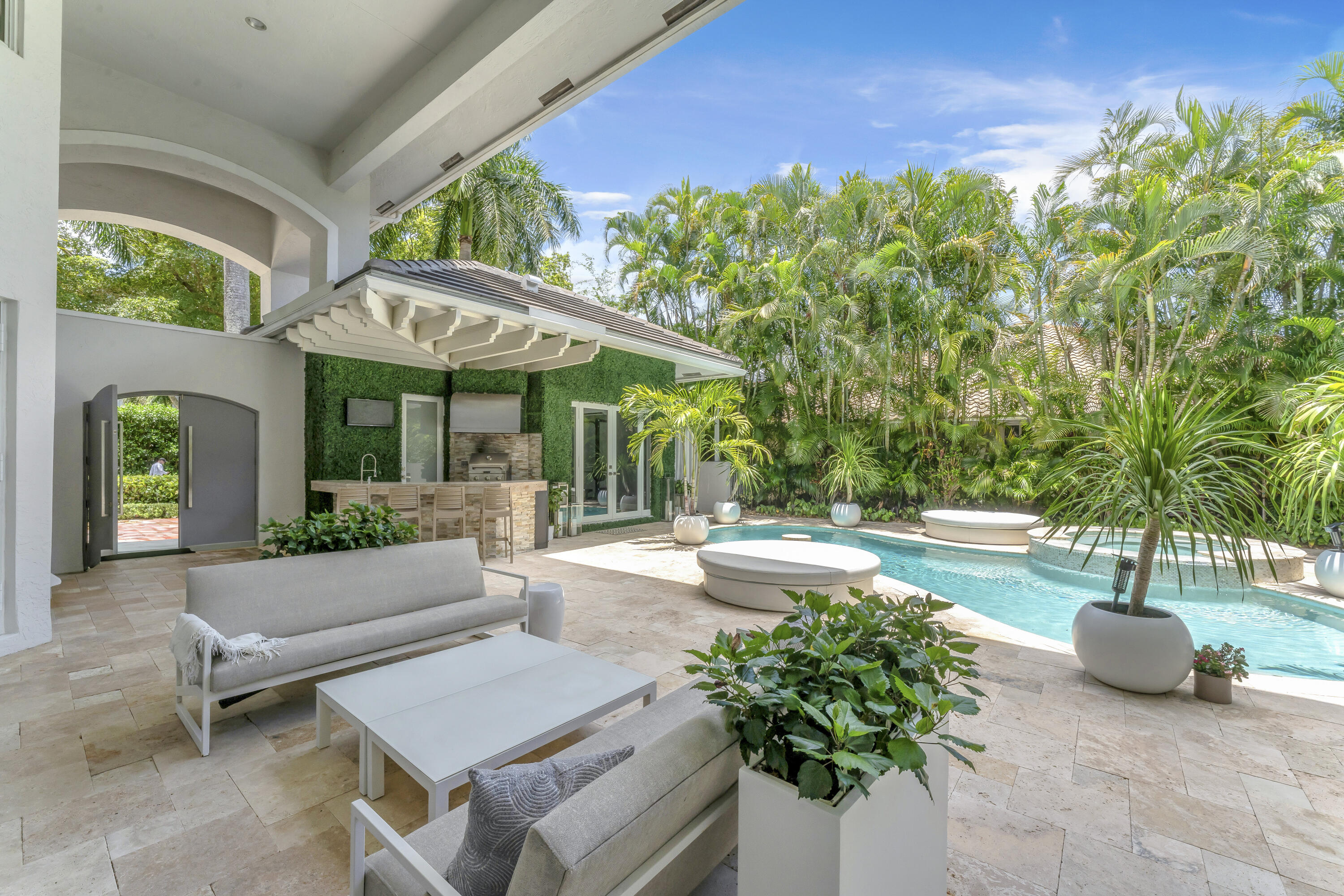 3156 Northwest 61st Street Boca Raton, FL 33496 - Photo 37 of 46 a view of a patio with couches and table and chairs under an umbrella with potted plants