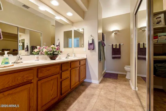 a spacious bathroom with a double vanity sink a toilet a mirror and shower