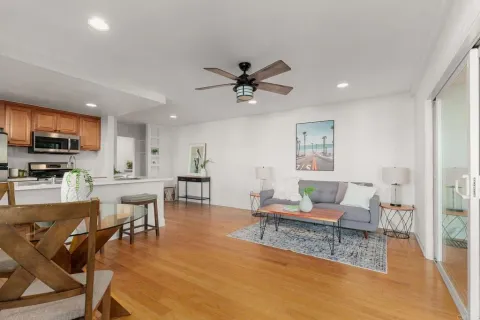 a living room with furniture kitchen view and a wooden floor