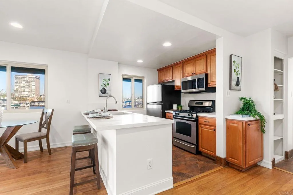 1202 North Pacific Street, Unit 101B Oceanside, CA 92054 - Photo 19 of 48 a kitchen with stainless steel appliances a stove a sink a microwave a dining table and chairs