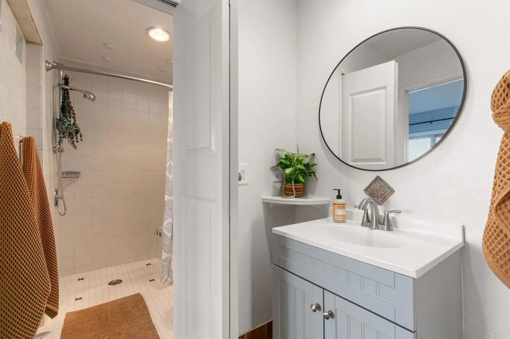 1202 North Pacific Street, Unit 101B Oceanside, CA 92054 - Photo 27 of 48 a bathroom with a sink a mirror a vanity and a shower