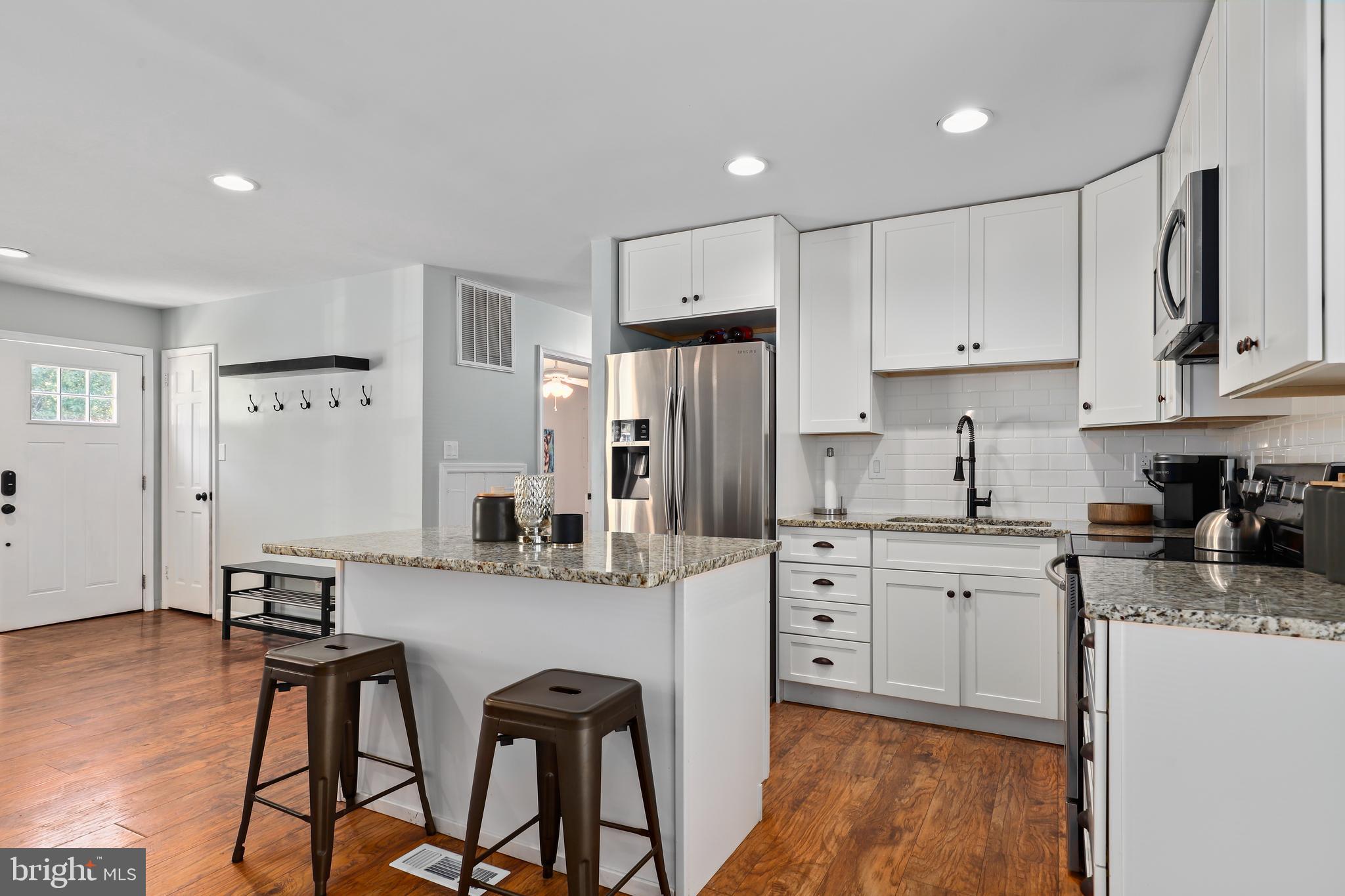 9422 Brentsville Road Manassas, VA 20112 - Photo 12 of 37 a kitchen with stainless steel appliances white cabinets and wooden floors