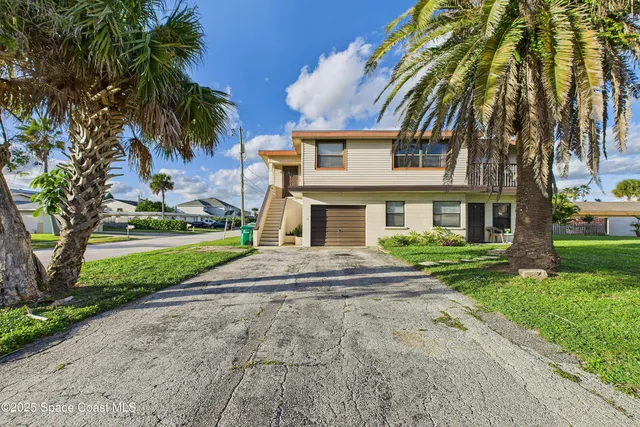 a front view of a house with a yard and palm trees