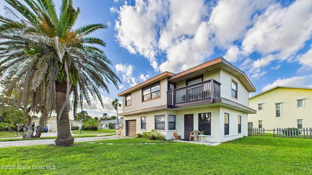 a view of a white house with a big yard and potted plants and large trees