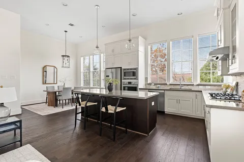 a very nice looking kitchen with granite countertop a sink dishwasher a dining table and chairs with wooden floor