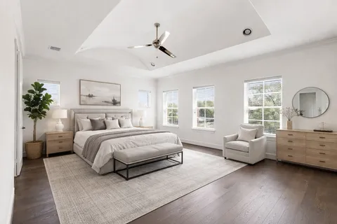 an empty room with wooden floor ceiling fan and windows