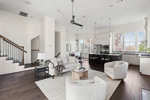 a living room with lots of furniture kitchen view and a wooden floor