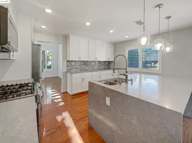 a view of an empty room with kitchen and window