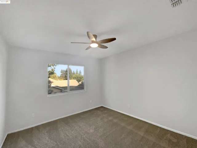 an empty room with closet and ceiling fan