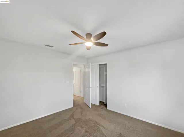 a view of a room with a ceiling fan and window