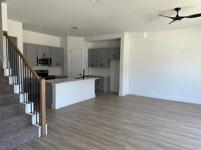 a view of kitchen with stainless steel appliances granite countertop a stove top oven a sink and a refrigerator
