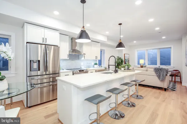 a kitchen with stainless steel appliances kitchen island granite countertop a sink a stove a refrigerator and island with wooden floor