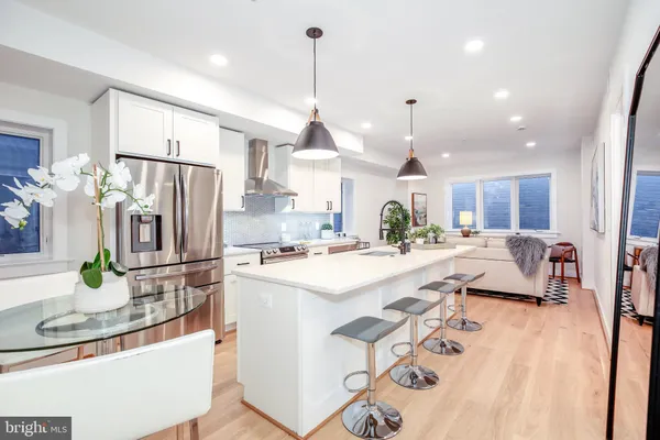 a kitchen with kitchen island a refrigerator a stove a sink a dining table and chairs