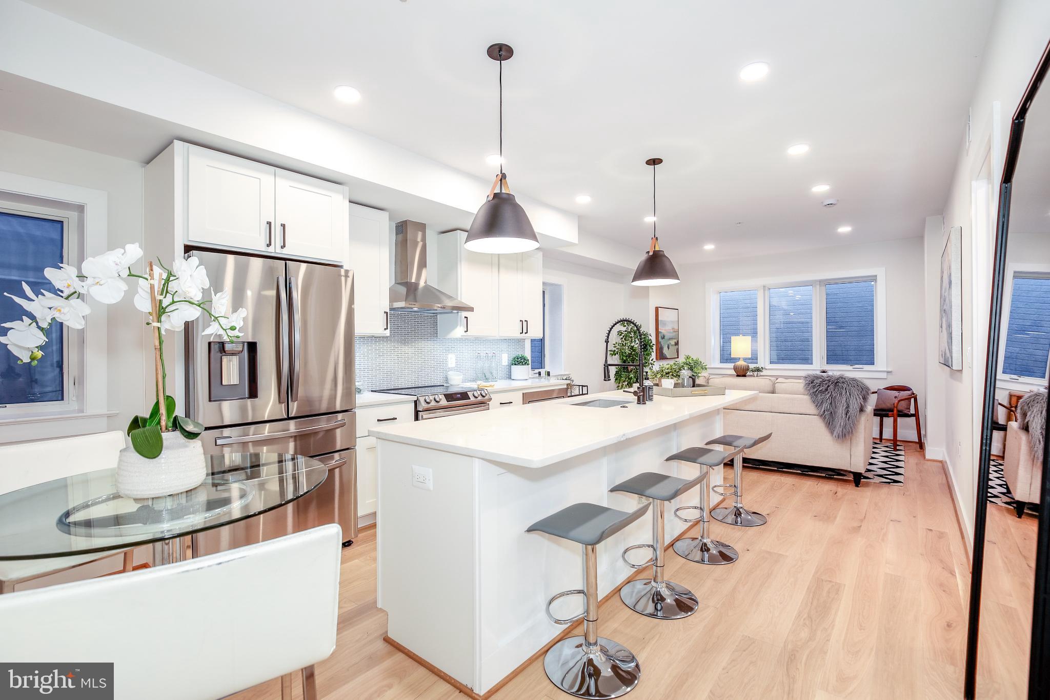 1009 Rhode Island Avenue Northeast, Unit 1 Washington, DC 20018 - Photo 2 of 21 a kitchen with kitchen island a refrigerator a stove a sink a dining table and chairs