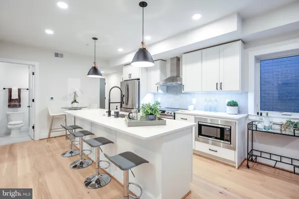 a kitchen with stainless steel appliances a sink a stove a center island and cabinets