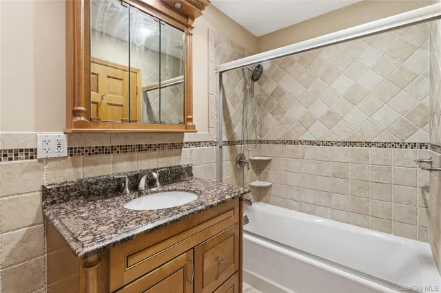 a bathroom with a granite countertop sink and a bathtub