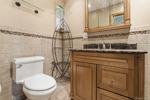 a bathroom with a granite countertop toilet sink and mirror