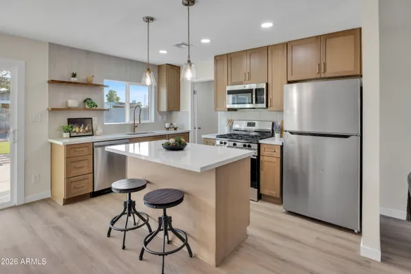 a kitchen with stainless steel appliances granite countertop a refrigerator a stove a sink dishwasher and a refrigerator with wooden floor