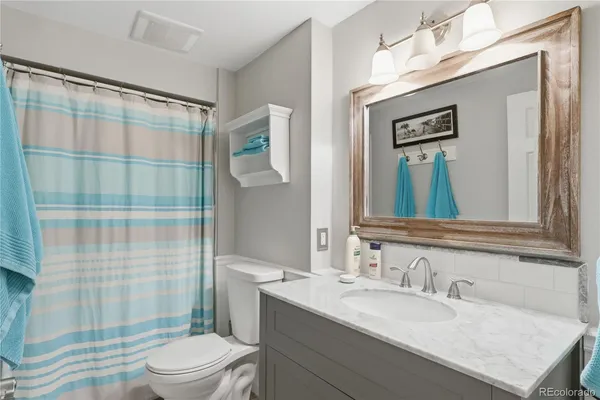 a bathroom with a granite countertop sink toilet a mirror a vanity and shower