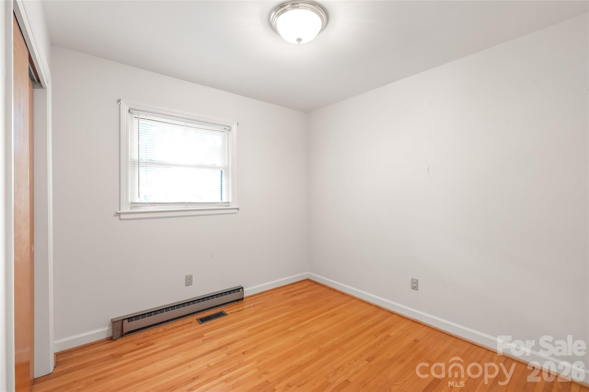 105 West Sunset Drive Locust, NC 28097 - Photo 17 of 24 an empty room with wooden floor and windows