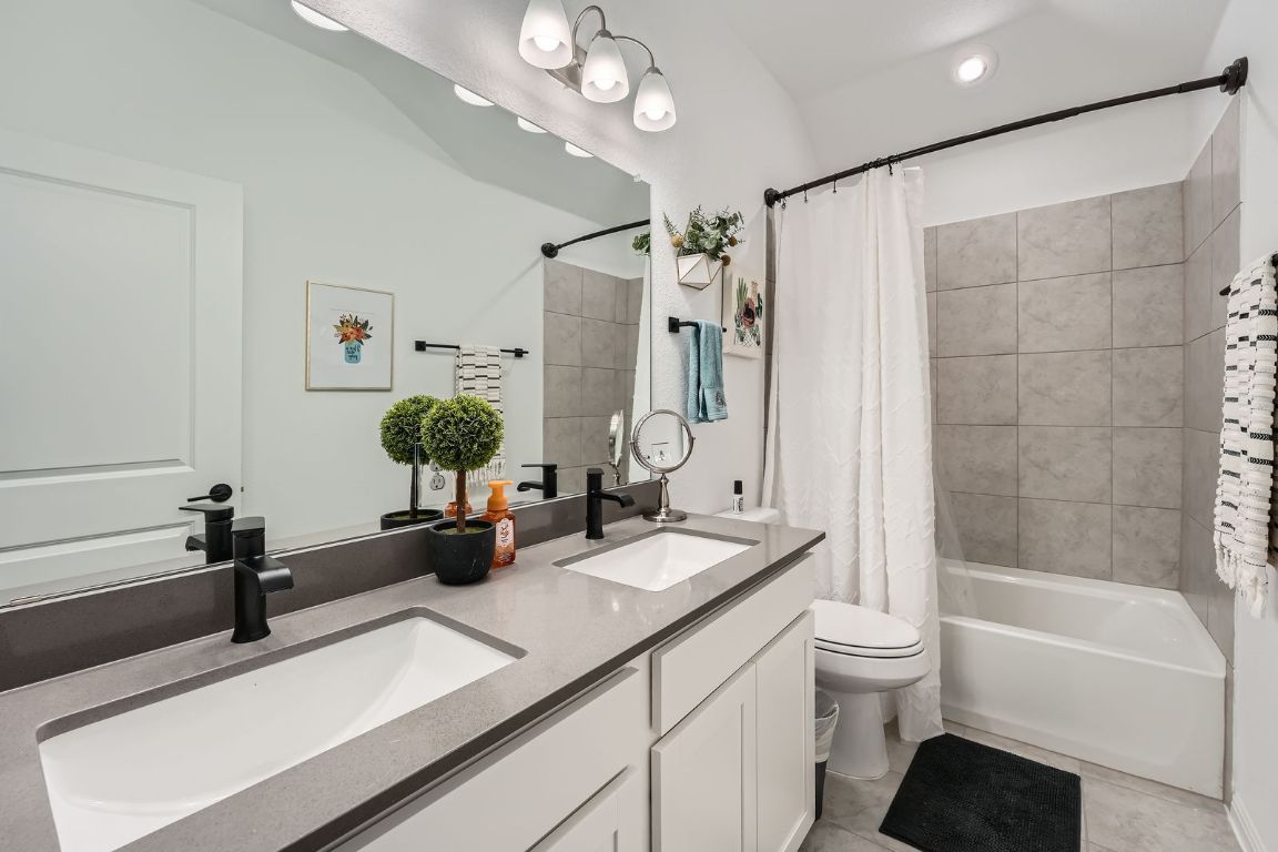 321 Georgia Lace Trail Georgetown, TX 78626 - Photo 20 of 28 Bathroom with double vanity, shower / bathtub combination with curtain, and light tile patterned flooring